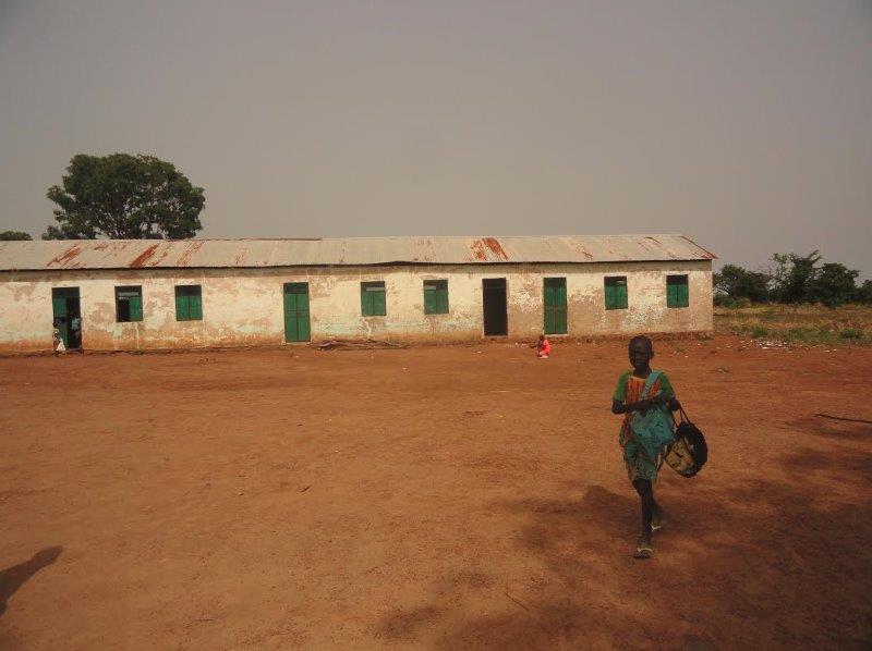A child walks in front of a long school building